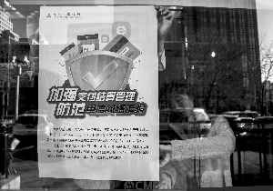 昨日，招商银行朝外大街支行工作人员在该行ATM机位置张贴《加强支付结算管理防范电信网络新型违法犯罪有关事项的通知》。北京晨报记者 史春阳/摄