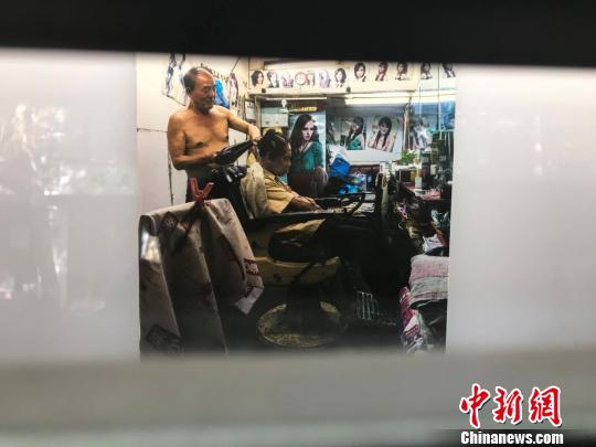 理发店里理发师正在为中年男人吹发。 王子涛 摄