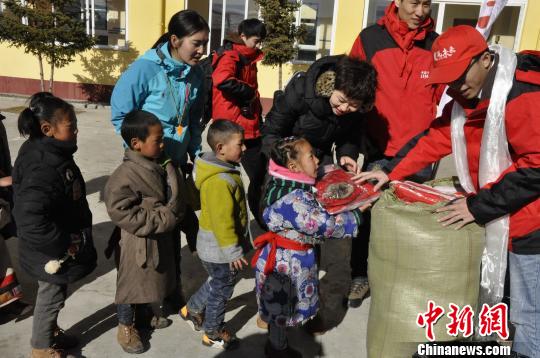 图为一个孩子在领取爱心物资的时候向志愿者说谢谢。 陈茂霖 摄