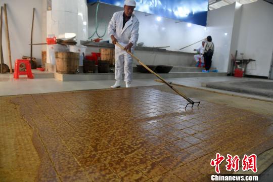冷却基本完成的红糖水结成块,师傅用特制的工具进行分块。 吕明 摄