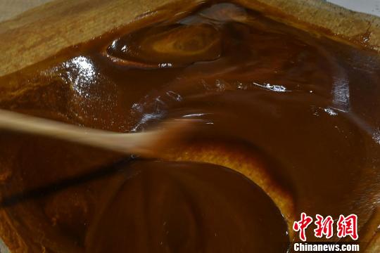 红糖水稠,师傅用器具将其搅匀。 吕明 摄