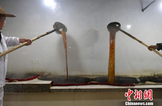 师傅们在大锅前耍着器具,慢火熬制红糖水。 吕明 摄