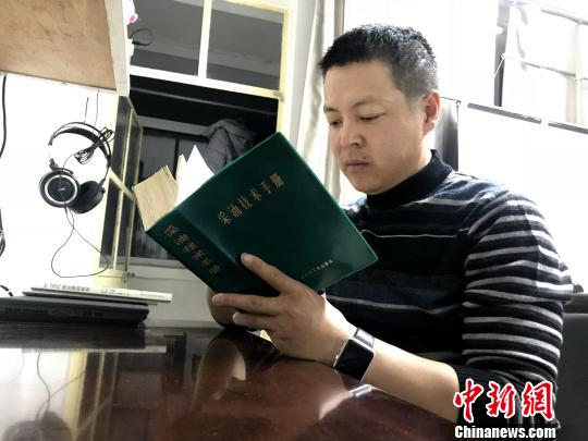 图为史昆在遇到不懂的问题时,经常翻看《采油技术手册》。 孙睿 摄