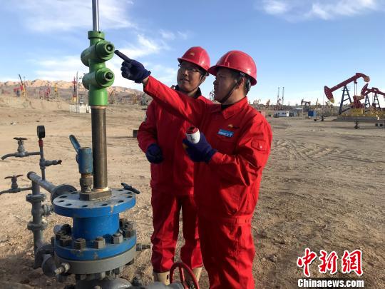 图为史昆(右)在采油作业区与工友一同交流。 孙睿 摄