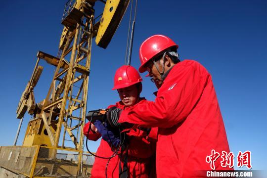 图为史昆(左一)与工友一起对测试的示功图及液面资料进行分析。 孙睿 摄