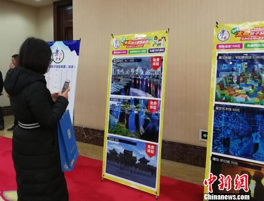 一位市民正在《2018太原亲子游览年票》相关介绍的展板前拍照。 杨杰英 摄