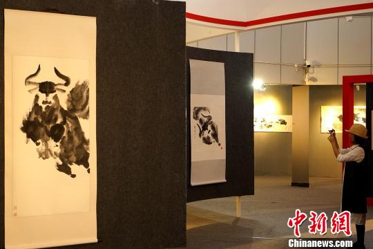 6月19日,一位观众在拉萨参观孟繁华水墨大写意牦牛个人画展,用手机拍摄绘画作品。 江飞波 摄