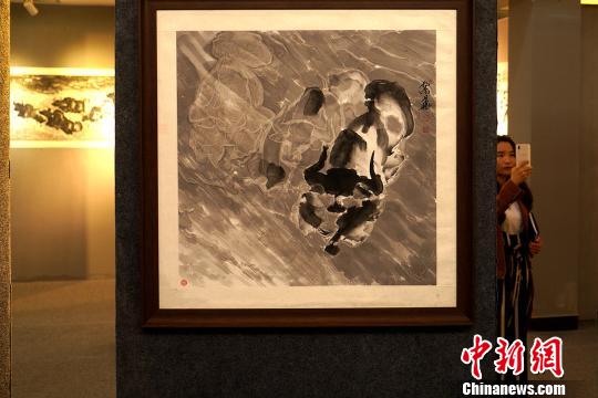 目前,孟繁华的绘画作品在西藏自治区群艺馆内展出。图为参加展览的观众浏览他创作的水墨写意牦牛画作品。 江飞波 摄